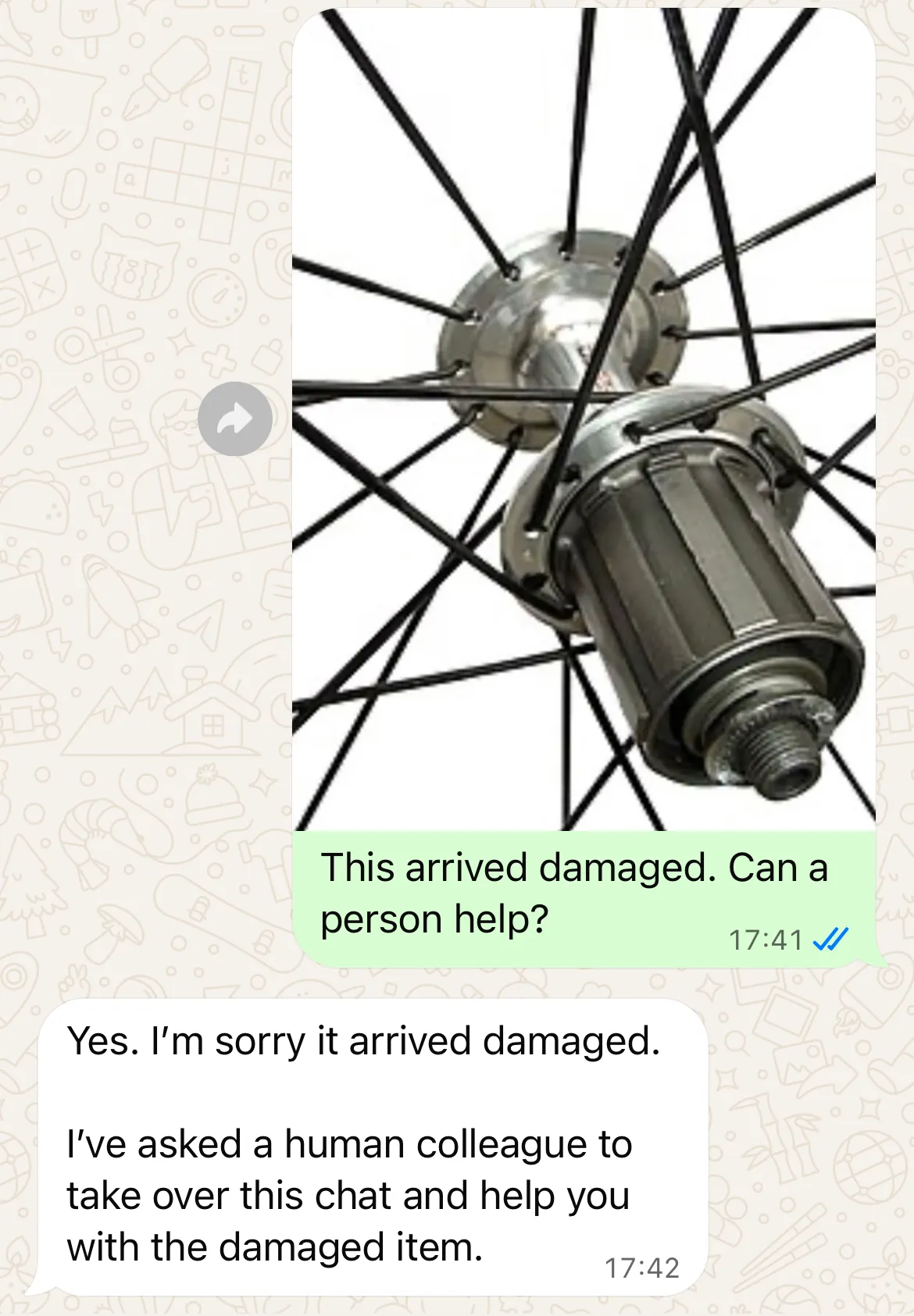 WhatsApp bicycle wheel photo with the caption This arrived damaged. Can a person help? and the reply transferring the conversation to the team
